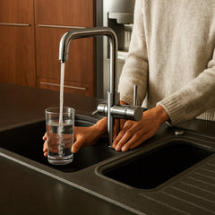 Person zapft Osmosewasser auf einem Wasserhahn