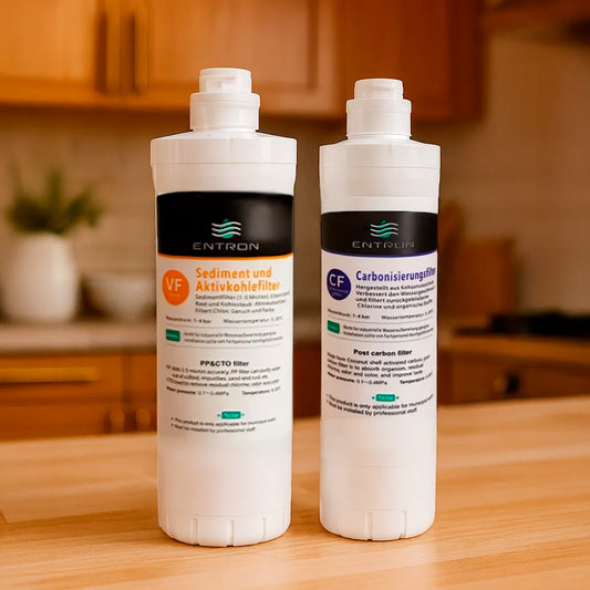 Das Ersatzfilter-Set bestehend aus: Sediment- und Aktivkohlefilter und Carbonisierungsfilter für die Entron F-Serie - stehend in einer warmen Küche